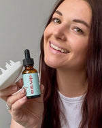 Woman holding a bottle of 'elevana' product and a white brush against a gray background