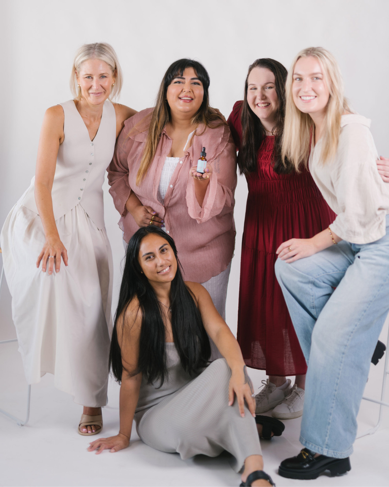 Five women posing together on a white background