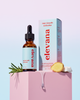 A bottle of elevana Hair Growth Activator next to its product box, styled on a pink pedestal with rosemary and ginger slices against a pastel gradient background.