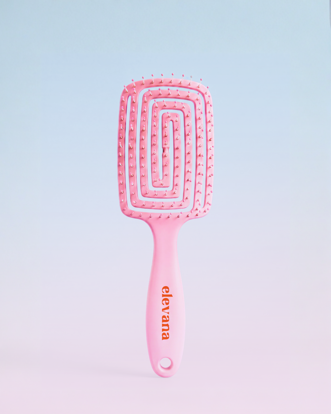 A pink hairbrush with a rectangular head, spiral bristle design, and a pink handle featuring the brand name 'elevana' in orange, set against a soft pastel blue-to-pink gradient background.