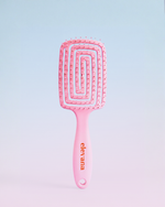 A pink hairbrush with a rectangular head, spiral bristle design, and a pink handle featuring the brand name 'elevana' in orange, set against a soft pastel blue-to-pink gradient background.